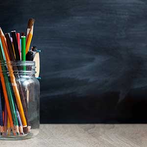 school desk with pens and an apple